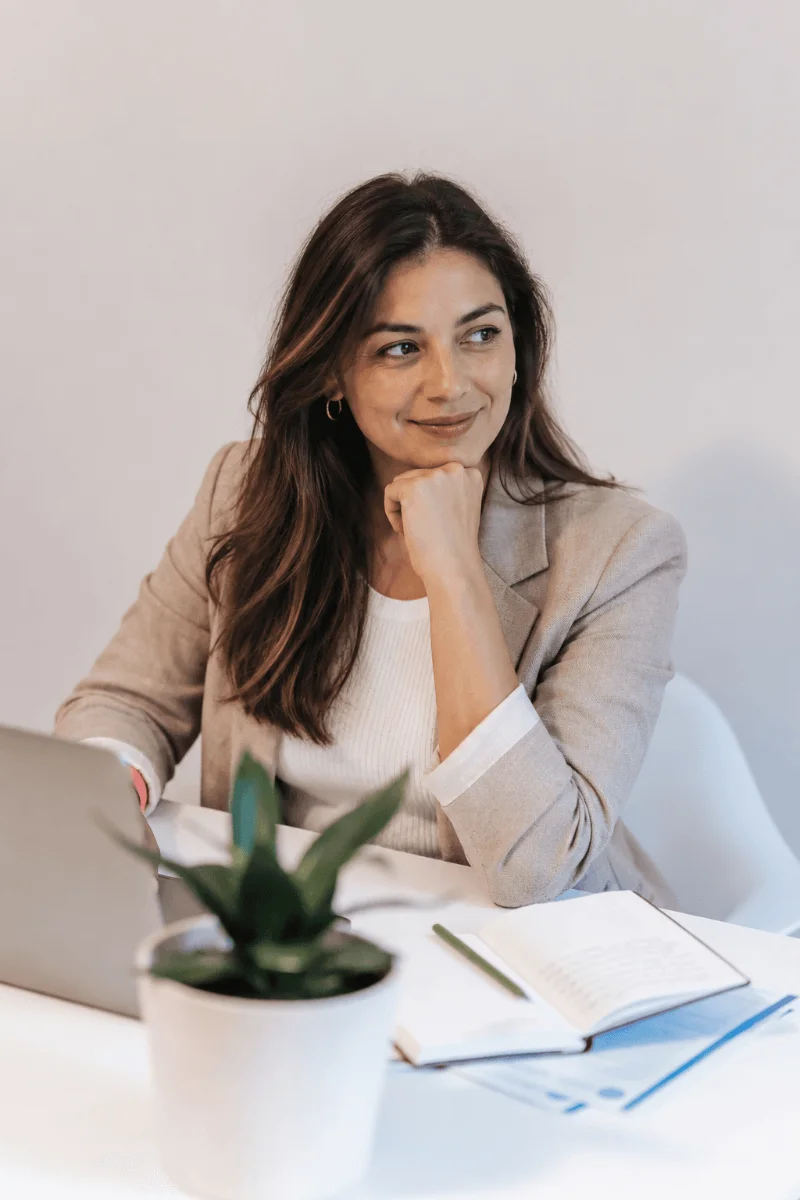 Mujer sonriendo frente a un laptop en su escritorio