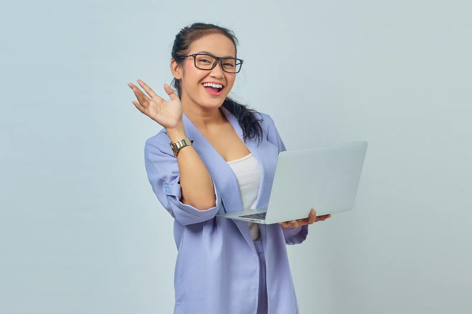 Profesional sonriendo y saludando con un laptop en la mano, representando el entrenamiento práctico de ventas y liderazgo con IA de MentorU
